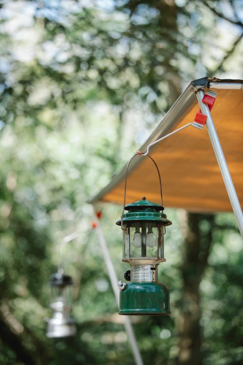 Free Old metal lantern hanging on hook on awning placed in forest for picnic Stock Photo