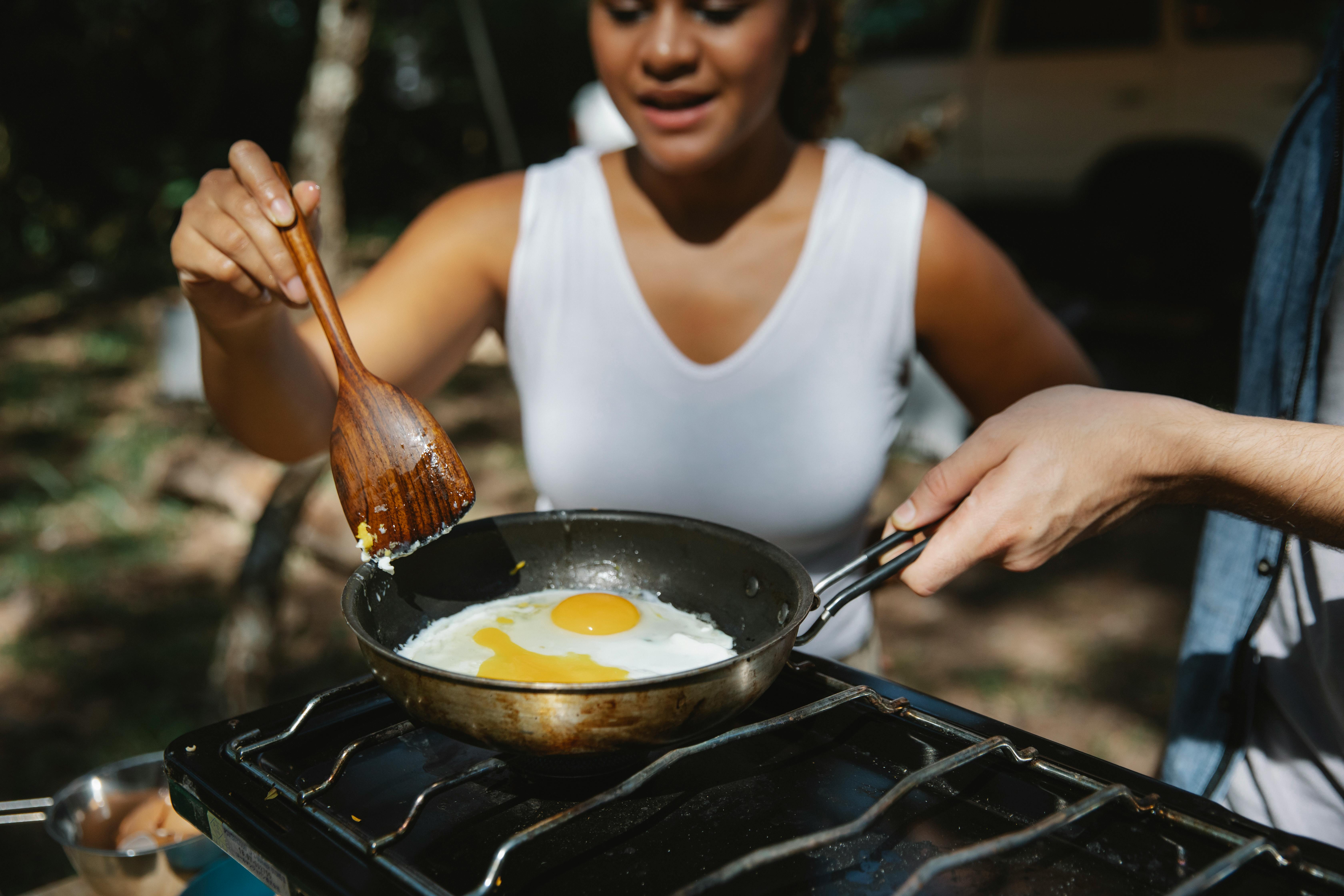 crop diverse couple cooking eggs on skillet