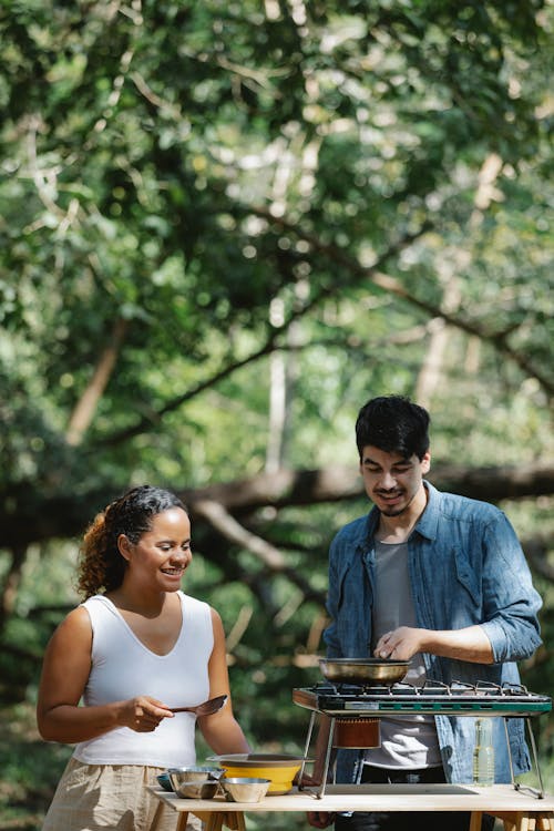 Happy multiracial couple cooking in forest