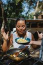 Positive ethnic woman looking at scrambled eggs