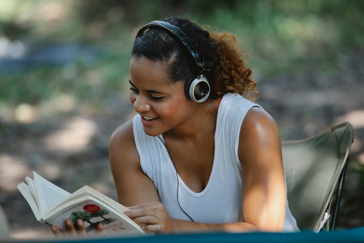 Smiling Ethnic Woman With Headphones Reading Book