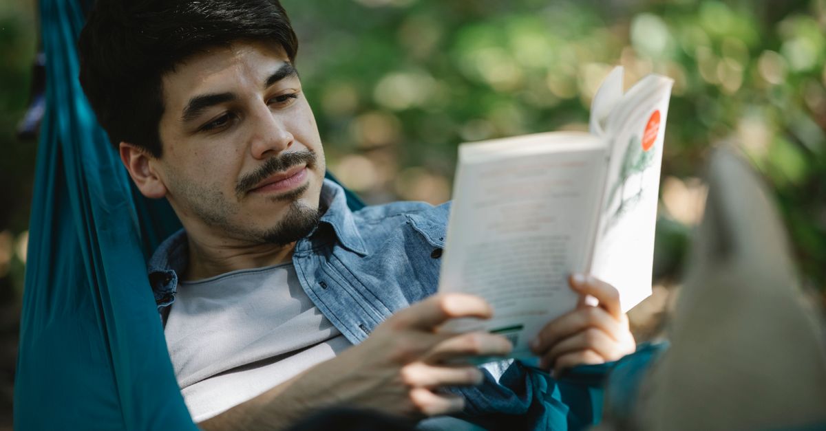 person reading a book in a hammock with a cup of tea, peaceful outdoor setting