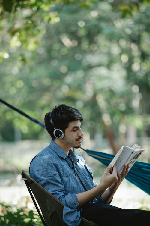 Free Focused young man reading book in park Stock Photo