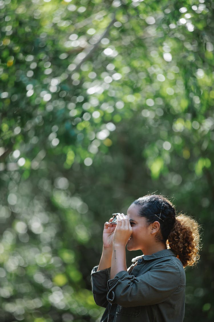 Positive Ethnic Woman With Binocular In Woods