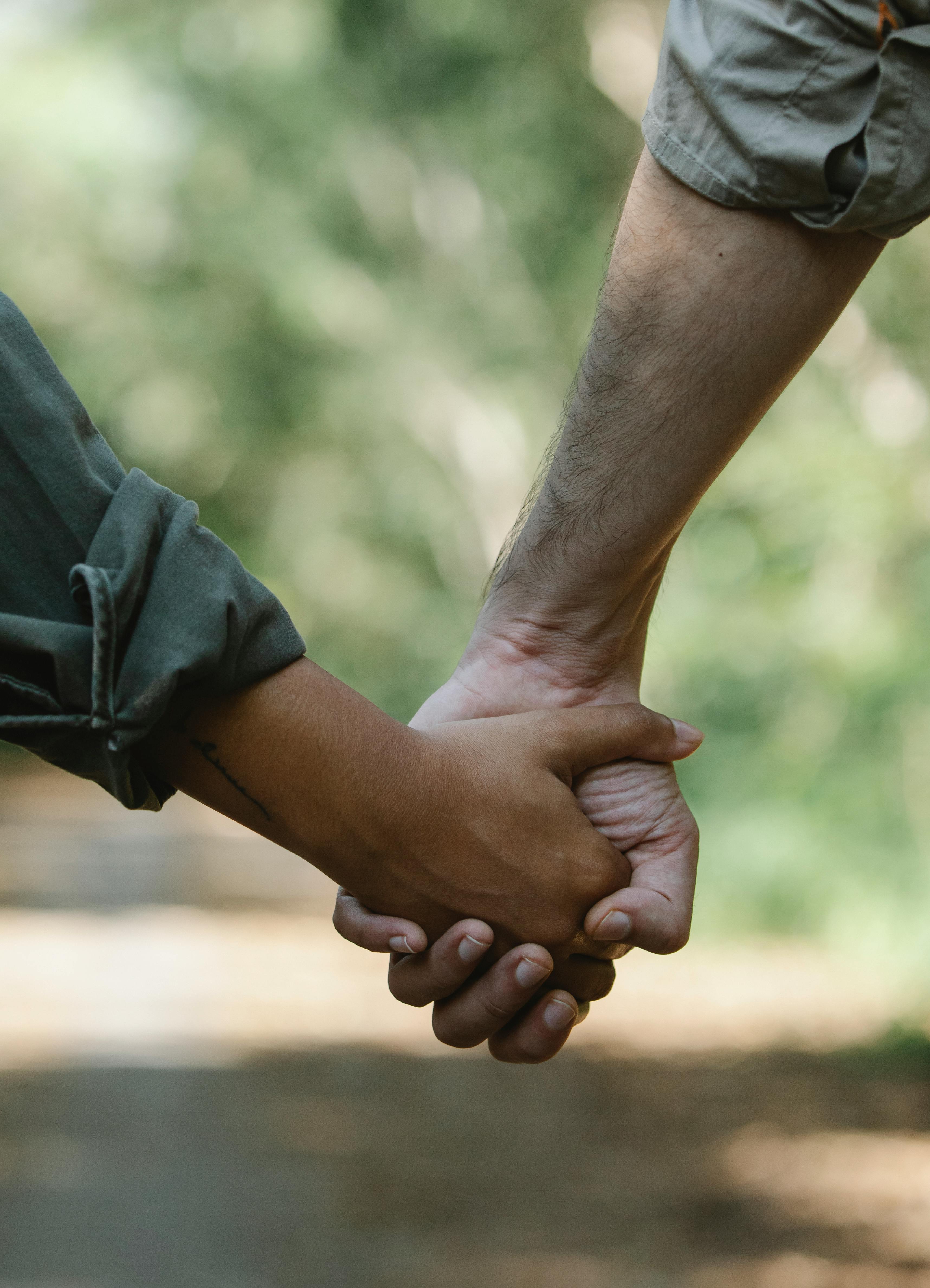 crop couple holding hands walking in park