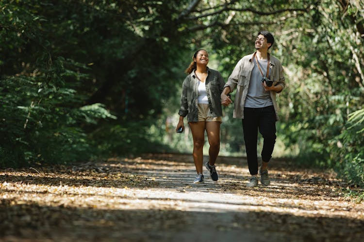 Smiling Diverse Couple Holding Hands Walking In Park