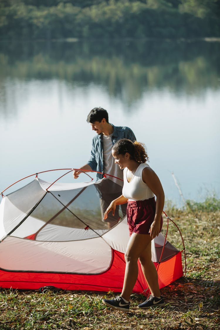 Young Couple Putting Up Tent On River Bank