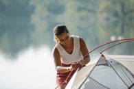 Focused traveler putting up tent near pond