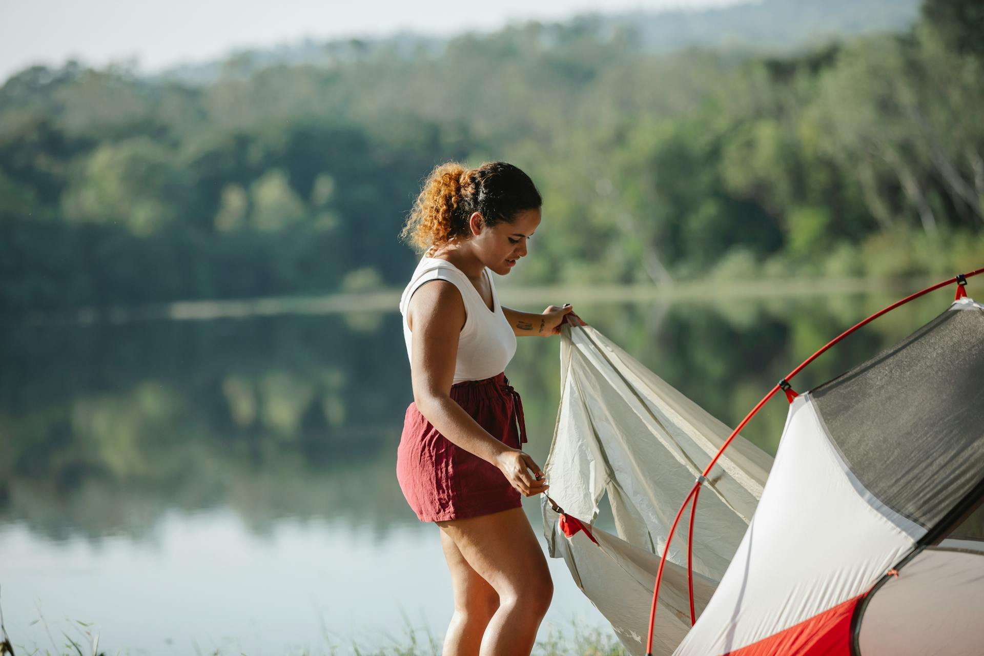 Young tourist putting up tent near river