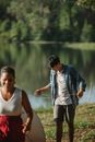 Diverse couple of tourists with tent on river bank