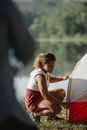 Concentrated tourist putting up tent on bank of river