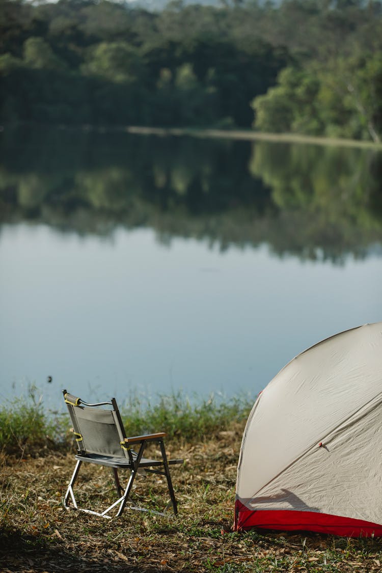 Tent With Camping Chair On Grass Against River