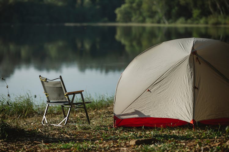 Tent And Portable Chair On River Shore In Summer