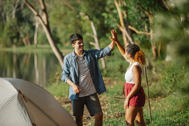 Content Diverse Couple Of Travelers Giving High Five In Campsite