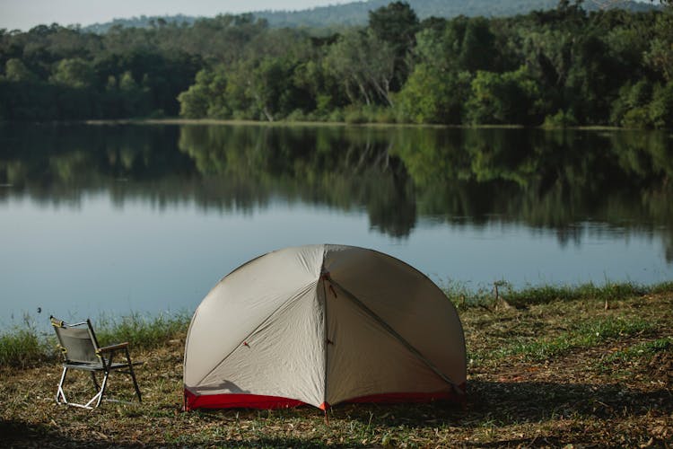 Tent And Camping Chair On River Shore In Summer