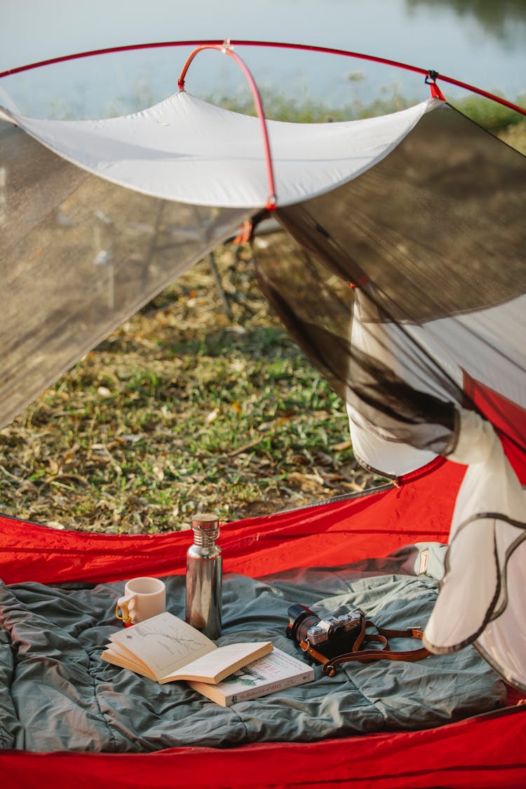 Camp Tent With Books And Thermos Bottle In Nature