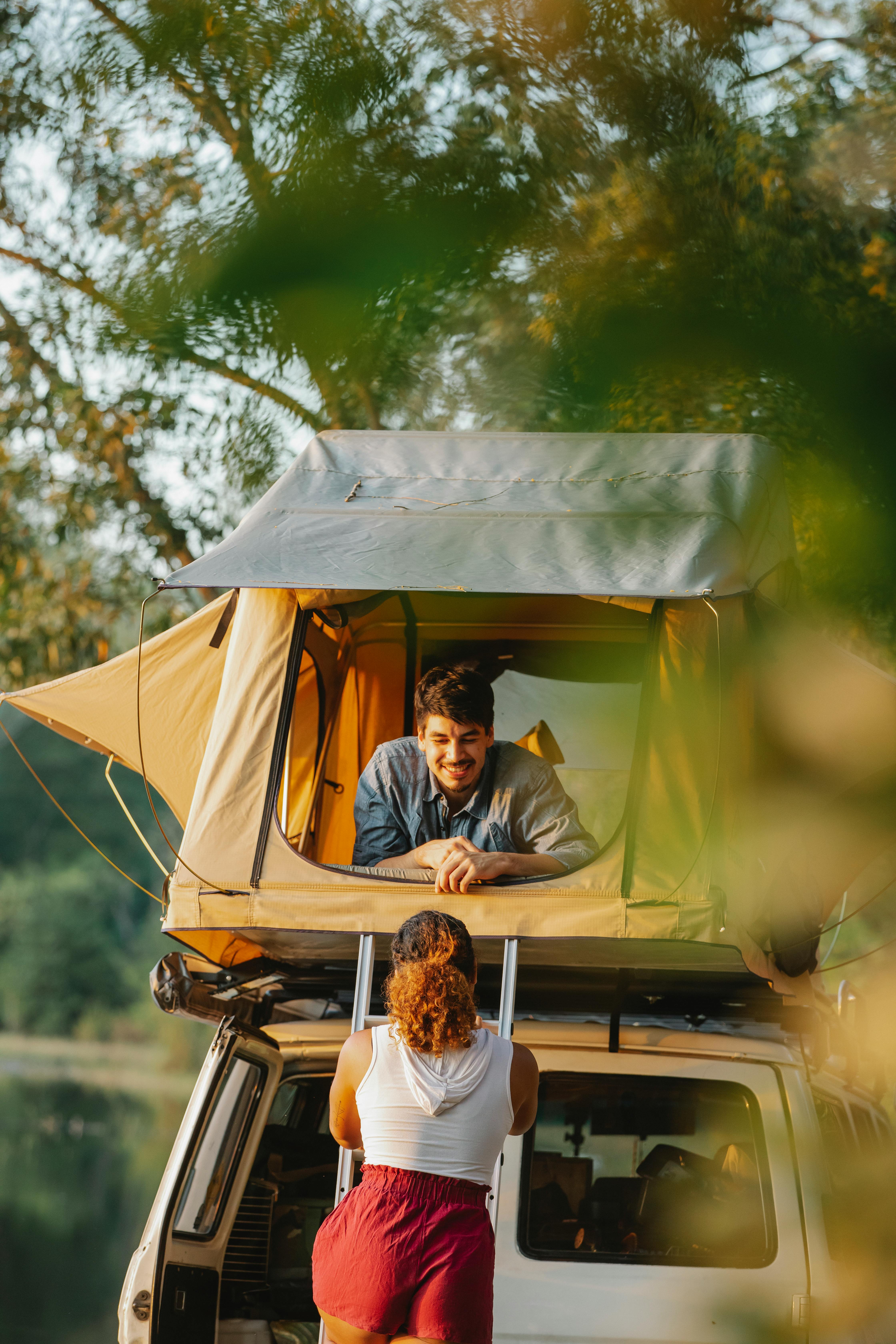 unrecognizable woman going upstairs towards boyfriend resting in camping tent