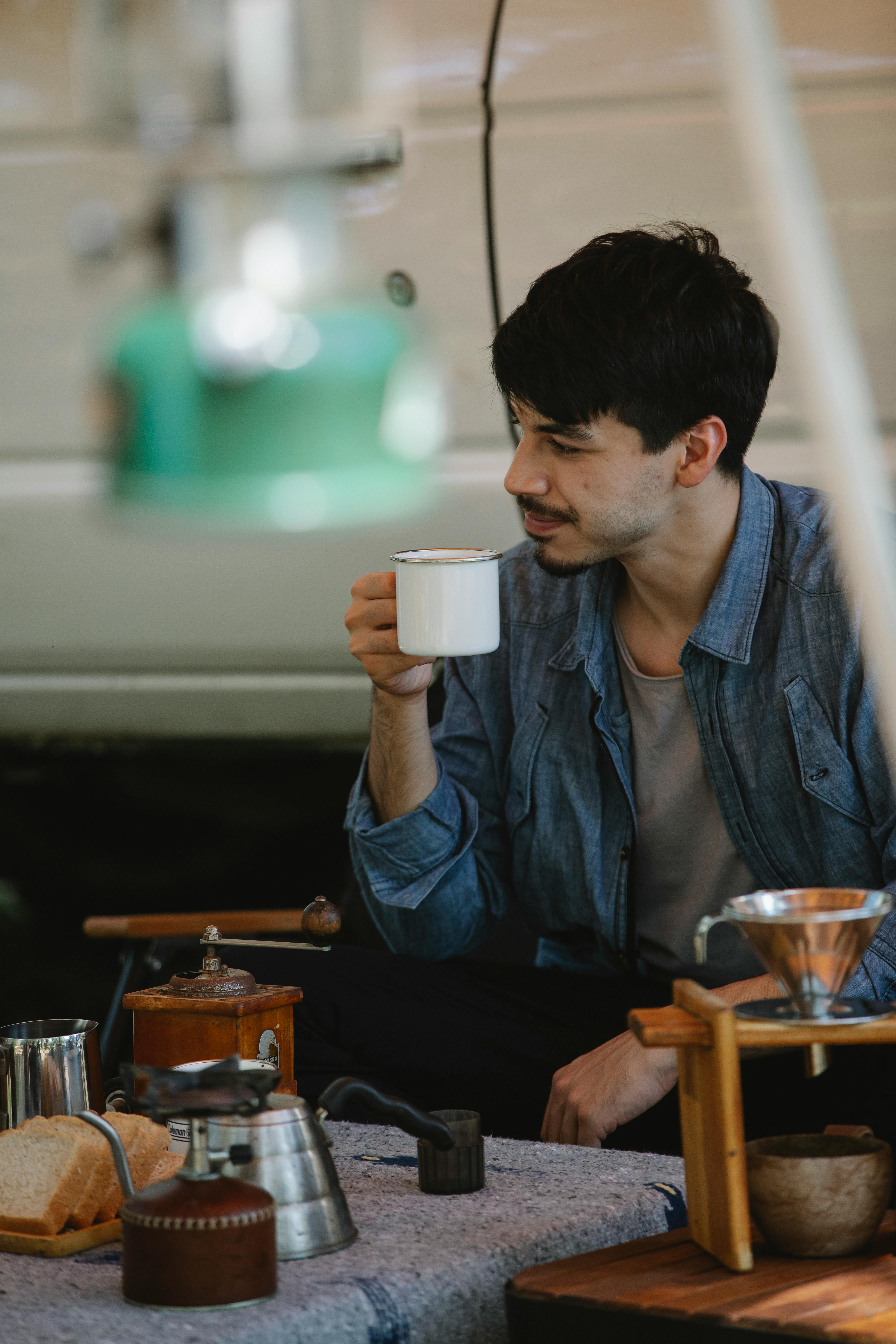 male tourist drinking tea on camp kitchen