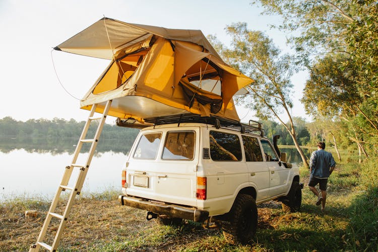 Man Putting Up Tent On Roof Of Car