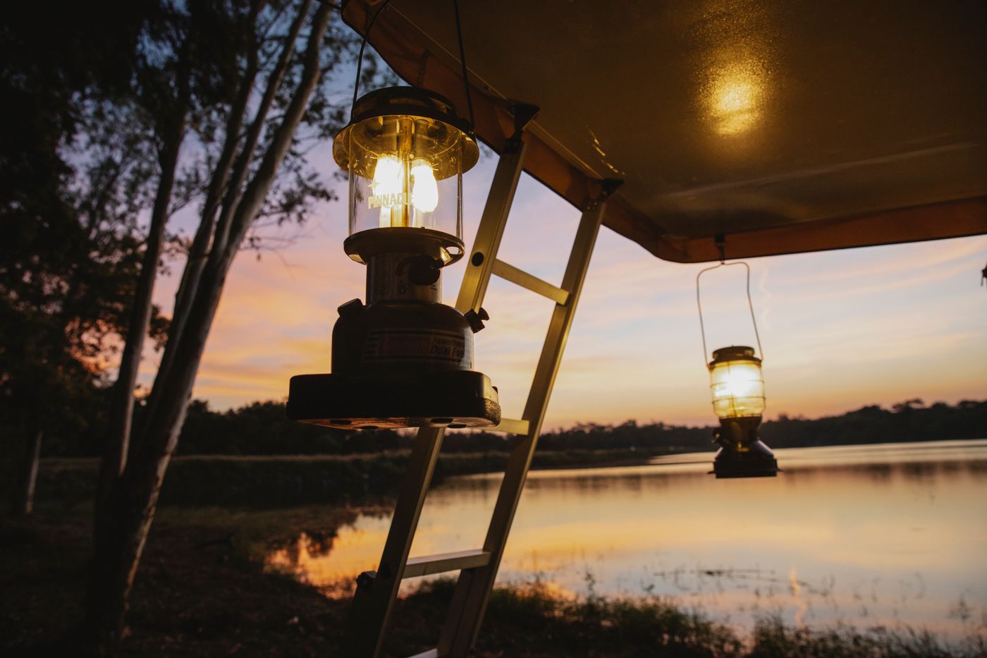 Coastal campsite with a tent and warm portable lamps at sunset