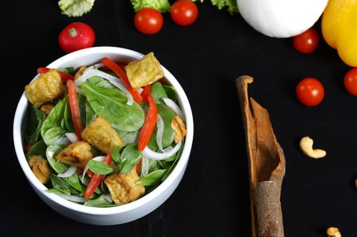 Free Colorful vegetable salad with crispy tofu, spinach, and fresh ingredients on black background. Stock Photo