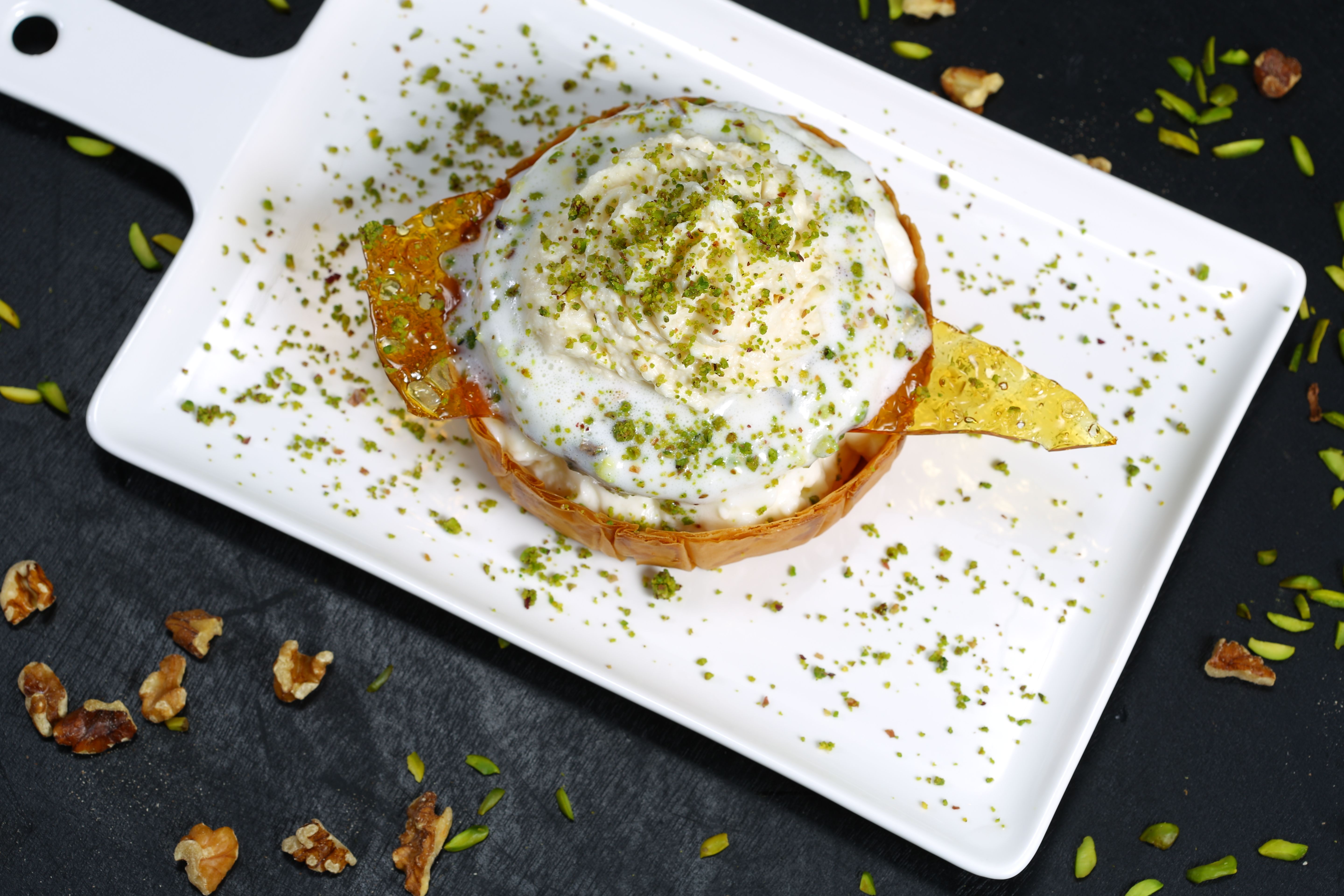 Close-up of a delicious kunefe dessert topped with ice cream and pistachios.