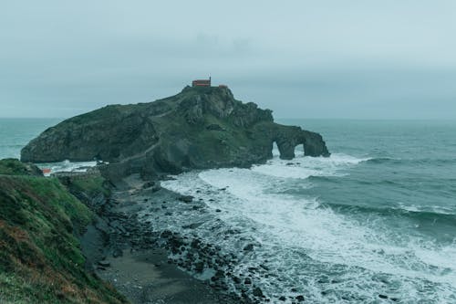 Rocky seacoast and island with church under foggy sky