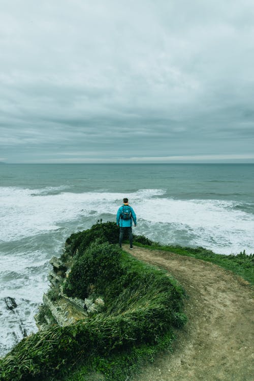 Man standing on edge of cliff above raging sea