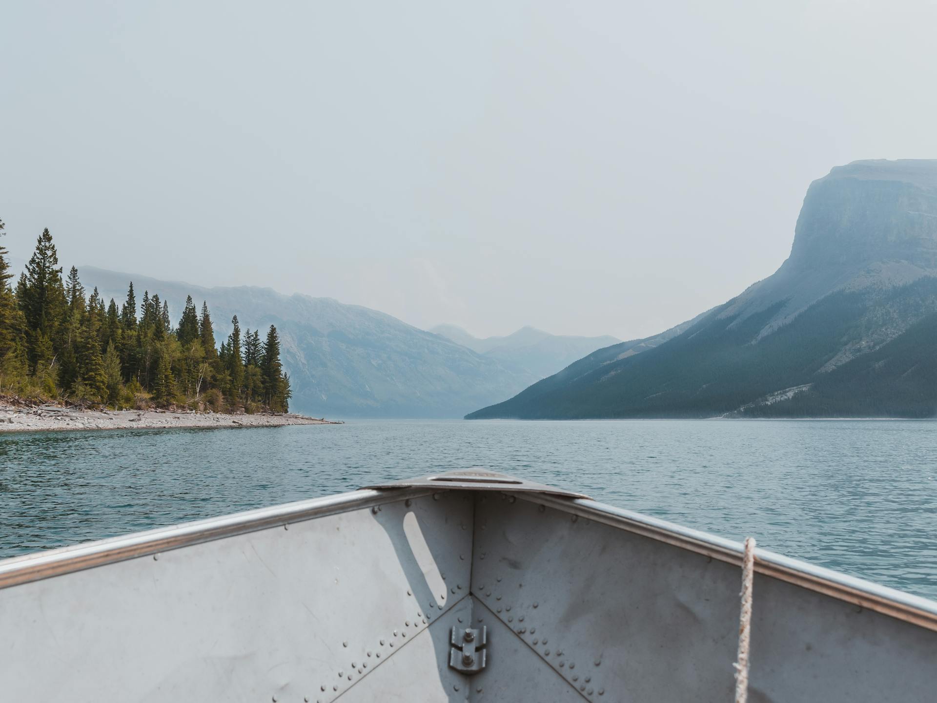 A peaceful boat ride on a tranquil lake surrounded by scenic mountains and lush forests.