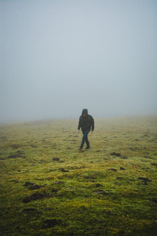 Faceless man walking on grassy hill