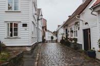 Narrow paved walkway on street between small residential buildings after raining in overcast weather