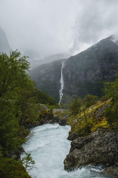 Free Picturesque landscape of foamy water of river flowing among rough rocky formations covered with green moss and trees Stock Photo
