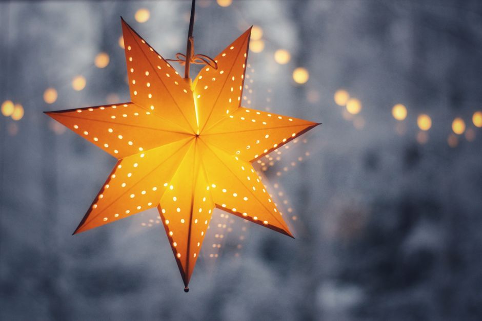 Fotomural Una linterna en forma de estrella iluminada cálidamente con luces bokeh en un fondo nevado de invierno.