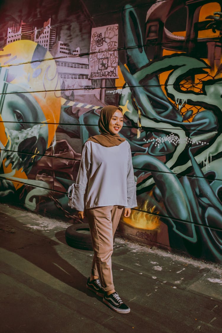 A Happy Young Woman Walking By Graffiti On A Wall