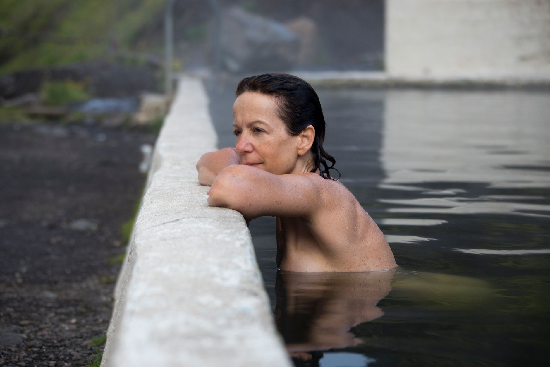 Caucasian woman enjoying a tranquil swim in an Icelandic geothermal pool.