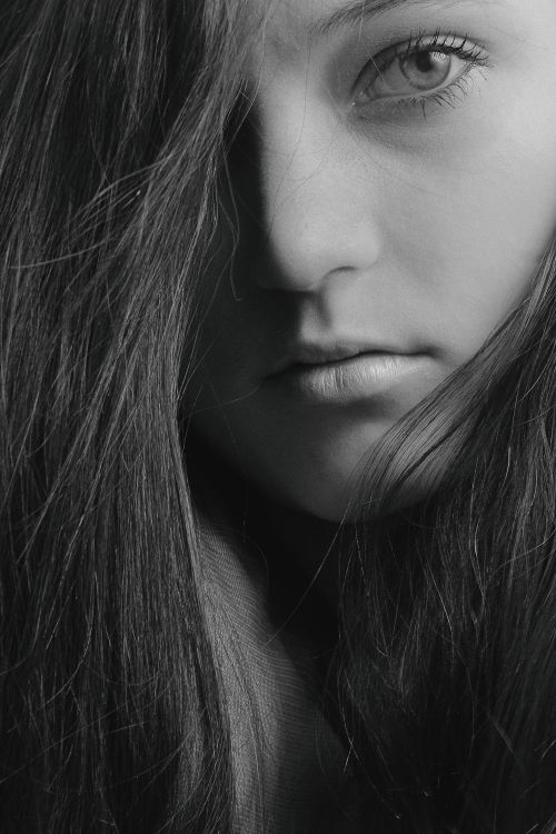Free Close-up black and white portrait of a young woman with intense gaze, showing depth and emotion. Stock Photo