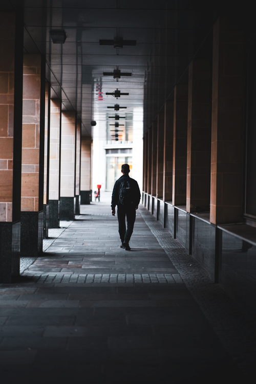 Free A solitary figure walks down a dimly lit corridor in London, England, creating a moody and introspective scene. Stock Photo