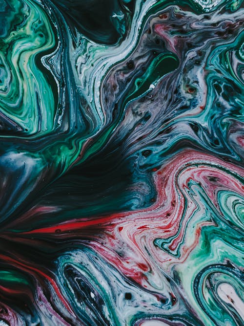 Top view of colorful acrylic paints flowing on surface and forming abstract swirls as background
