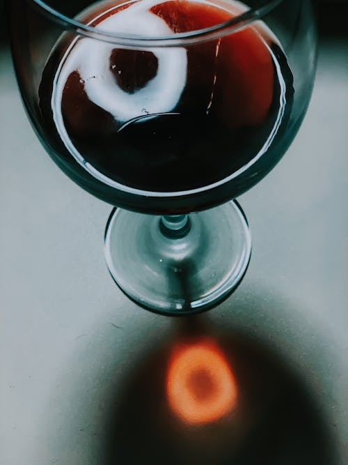 Free From above of glass of aromatic red wine placed on white table with shadow of glass Stock Photo