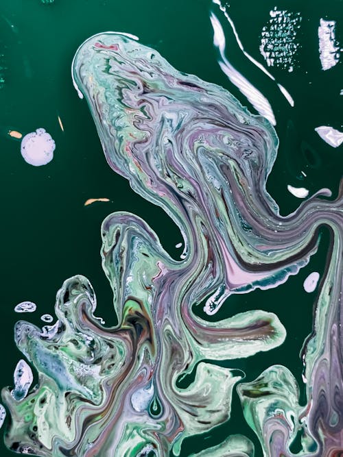 Top view of abstract background of colorful stains on surface of dark green water