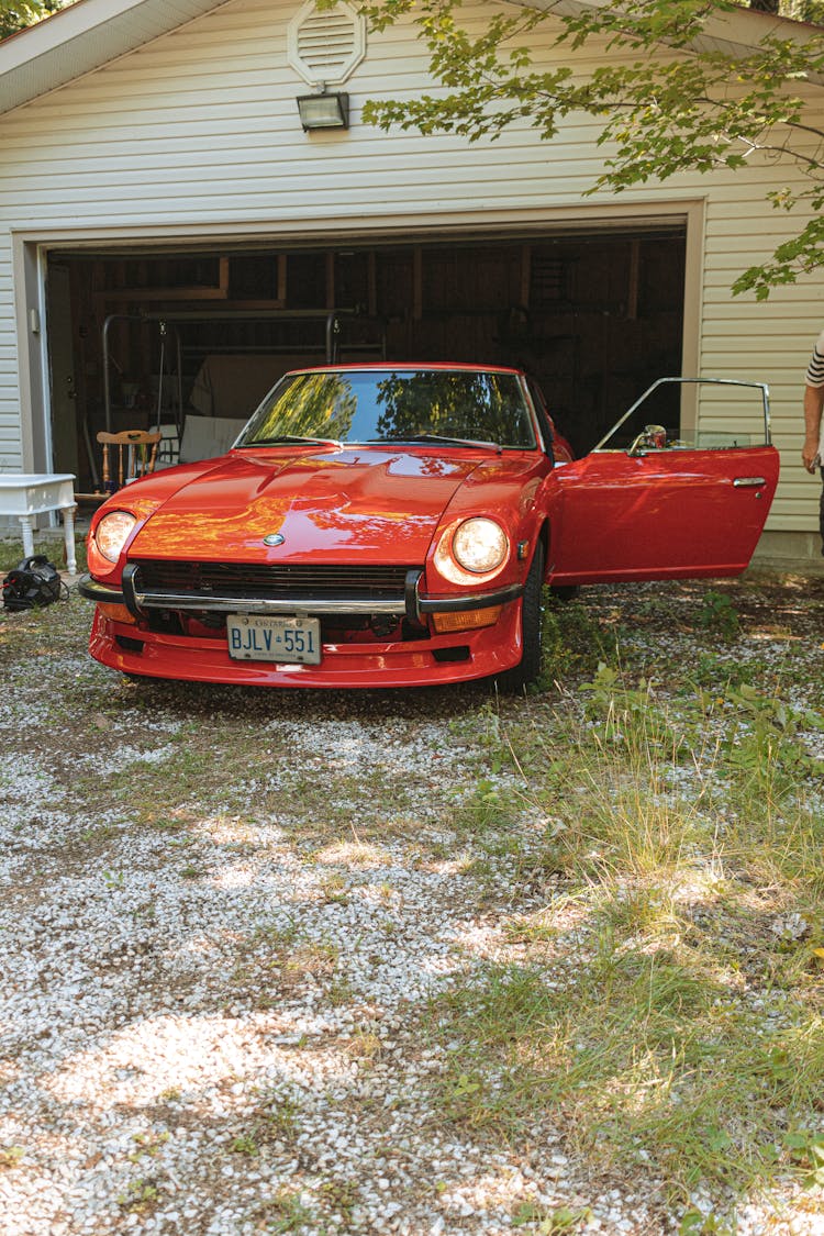 A Red Datsun 240z Parked In Front Of A Home Garage