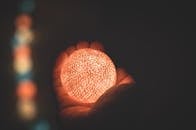 在黑暗中用手握住一个温暖的发光球体，以展示其发光效果和对比度