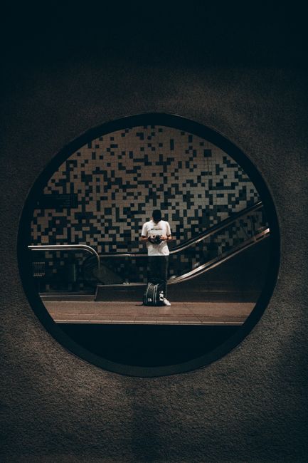 Abstract reflection of a person in a circular mirror in Rotterdam metro station.