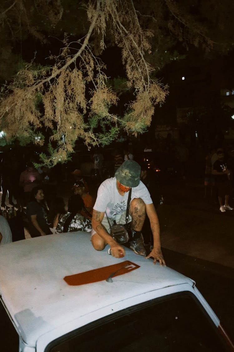 Man Spraying Roof Of Car At Night