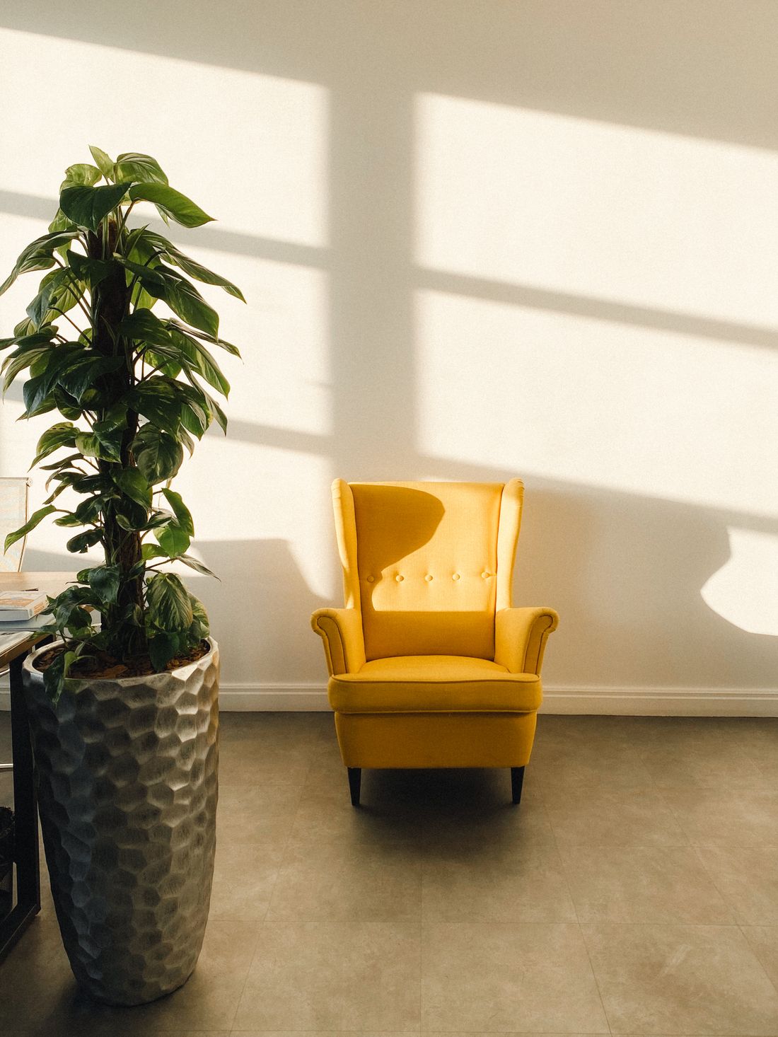 A warm, light-filled therapy room with a mustard armchair, plants and flowers