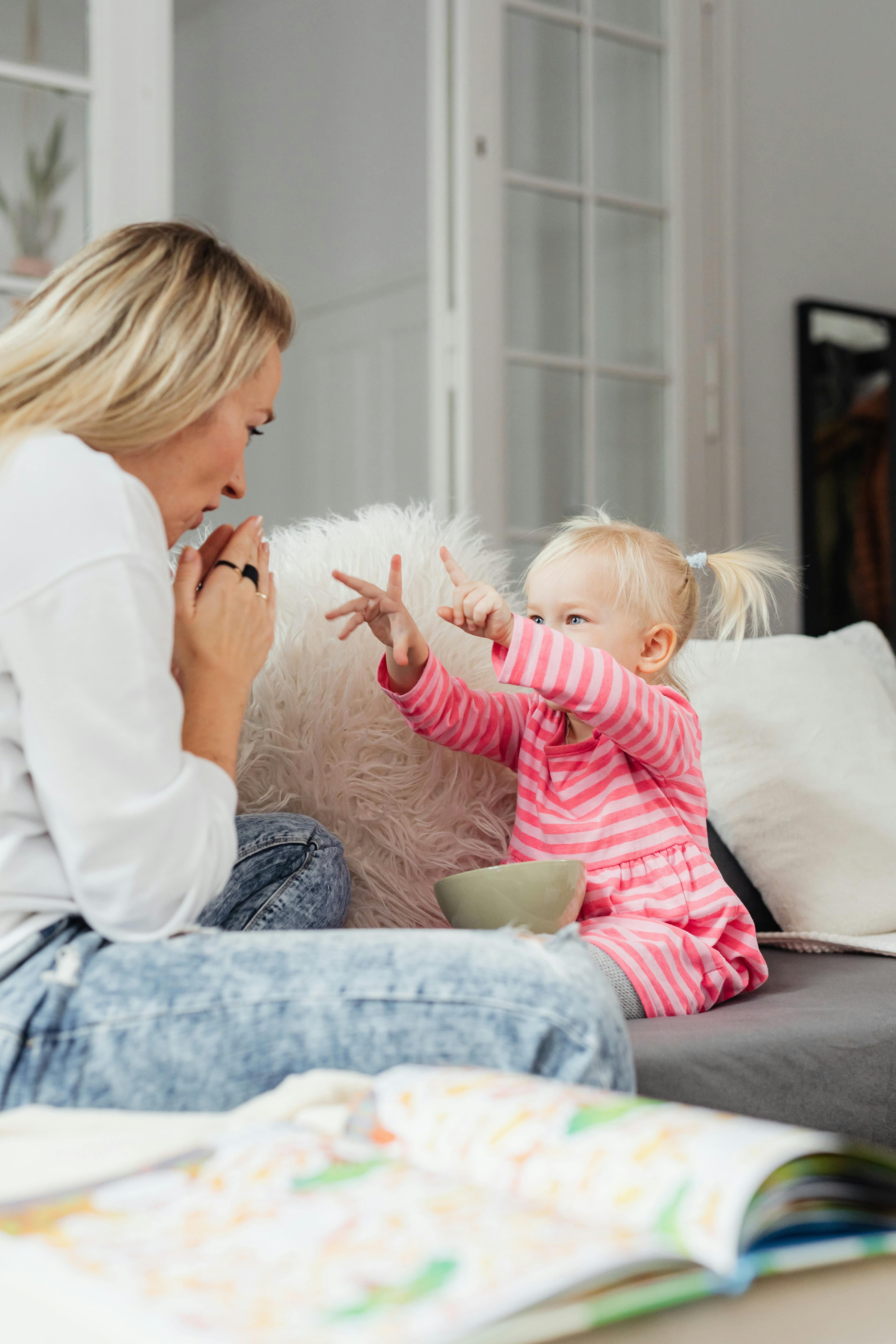 A mother and her daughter share a playful moment in a cozy living room setting.