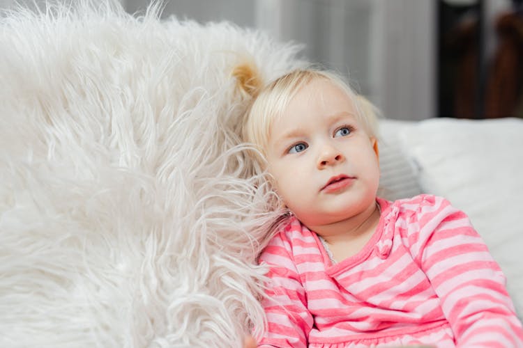 Selective Focus Photo Of A Girl In A Pink Shirt Laying On A Furry Pillow