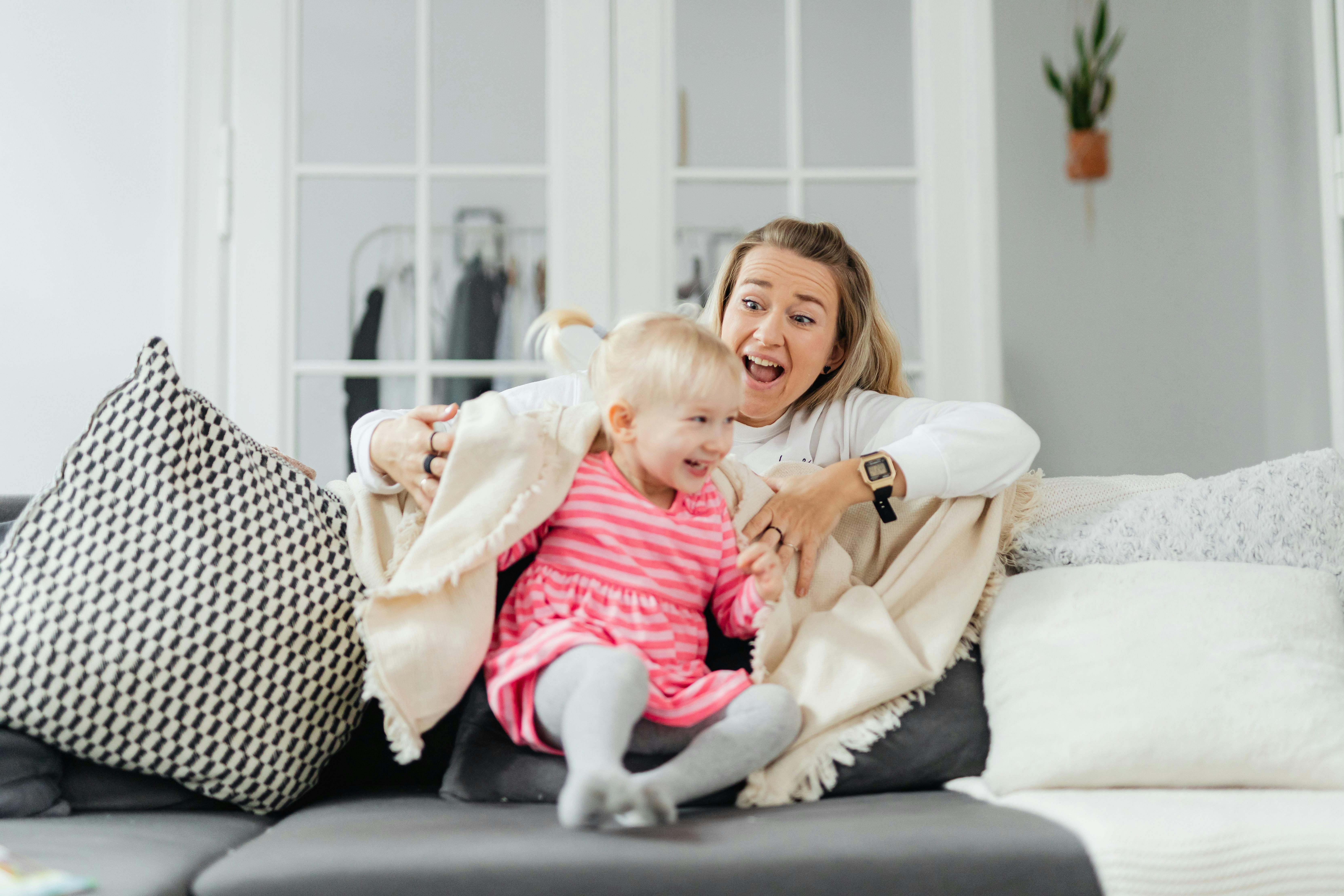 Mother and daughter play happily together on the couch, creating joyful family moments.
