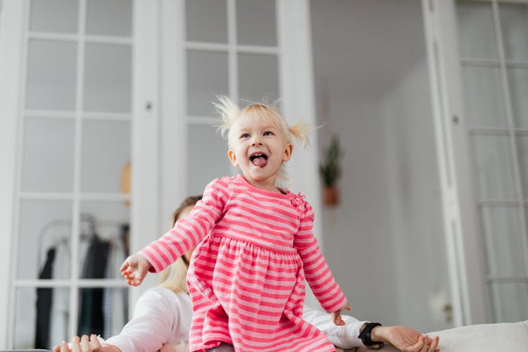 Little Girl In Pink Dress Jumping On Couch