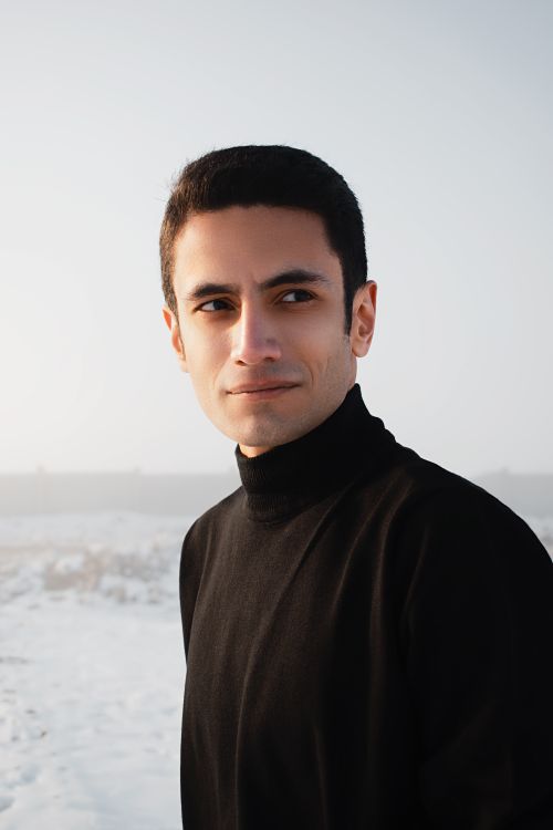 Free Serious young handsome male in black warm turtleneck in snowy terrain looking away Stock Photo